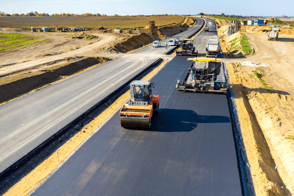 Road construction crew paving a new highway with asphalt paving machines and rollers