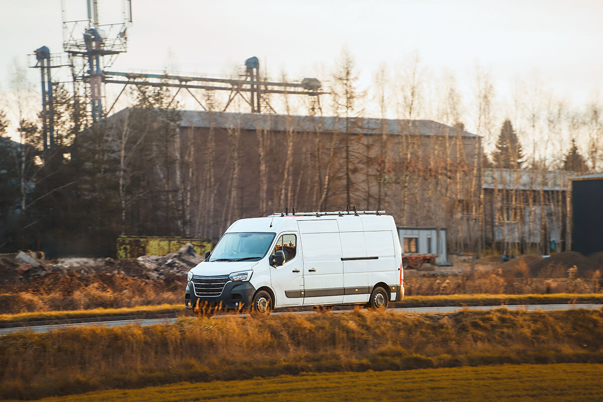 Commercial fleet van driving on a rural road with rooftop antennas installed for mobile connectivity