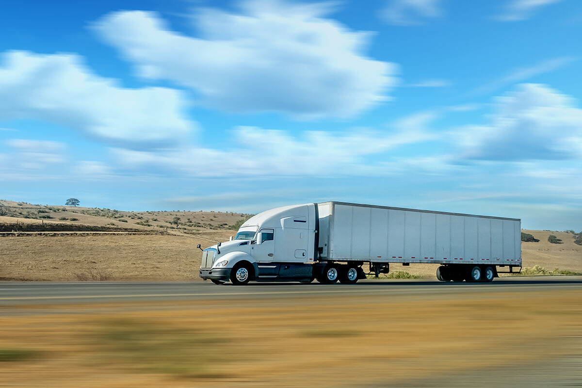 Commercial semi-truck traveling on a rural highway.